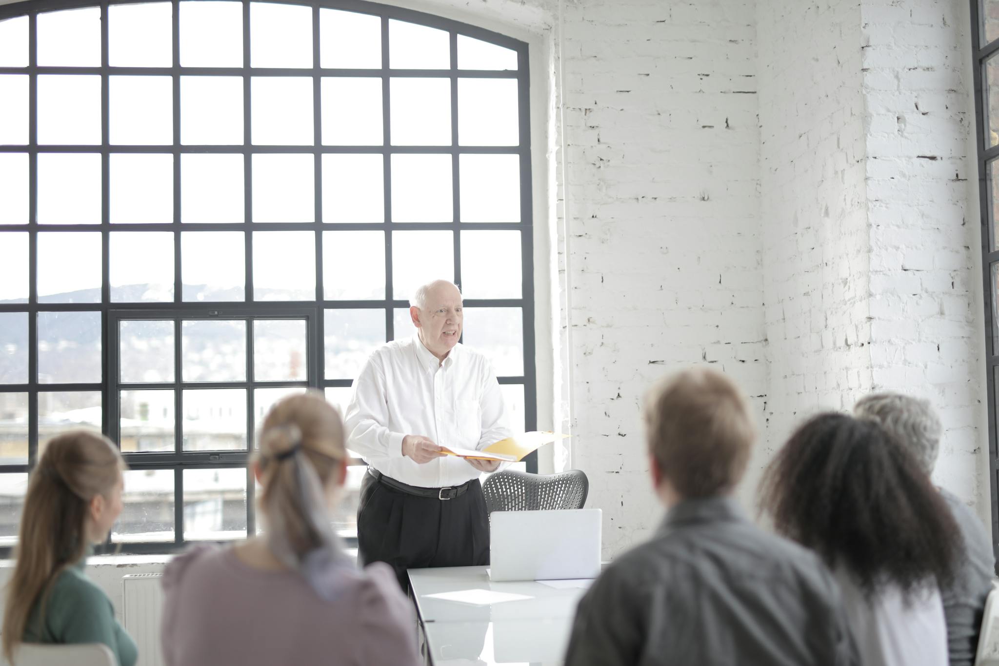 Diverse colleagues listening to senior male executive at meeting in office boardroom